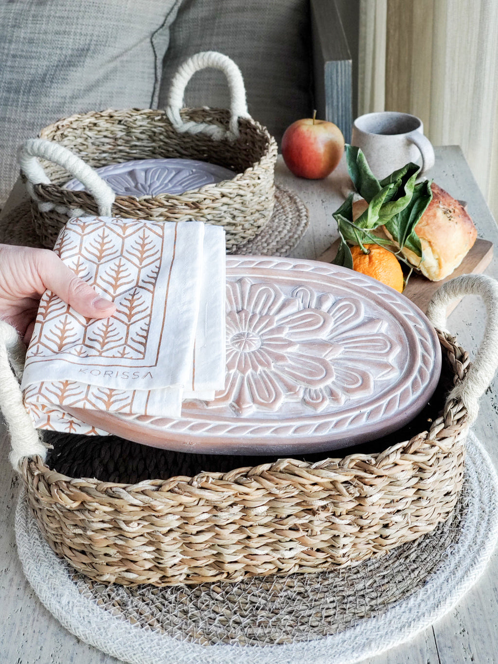 Terracotta bread warmer with engraved flower, woven seagrass serving basket, and natural cotton tea towel. — view 3