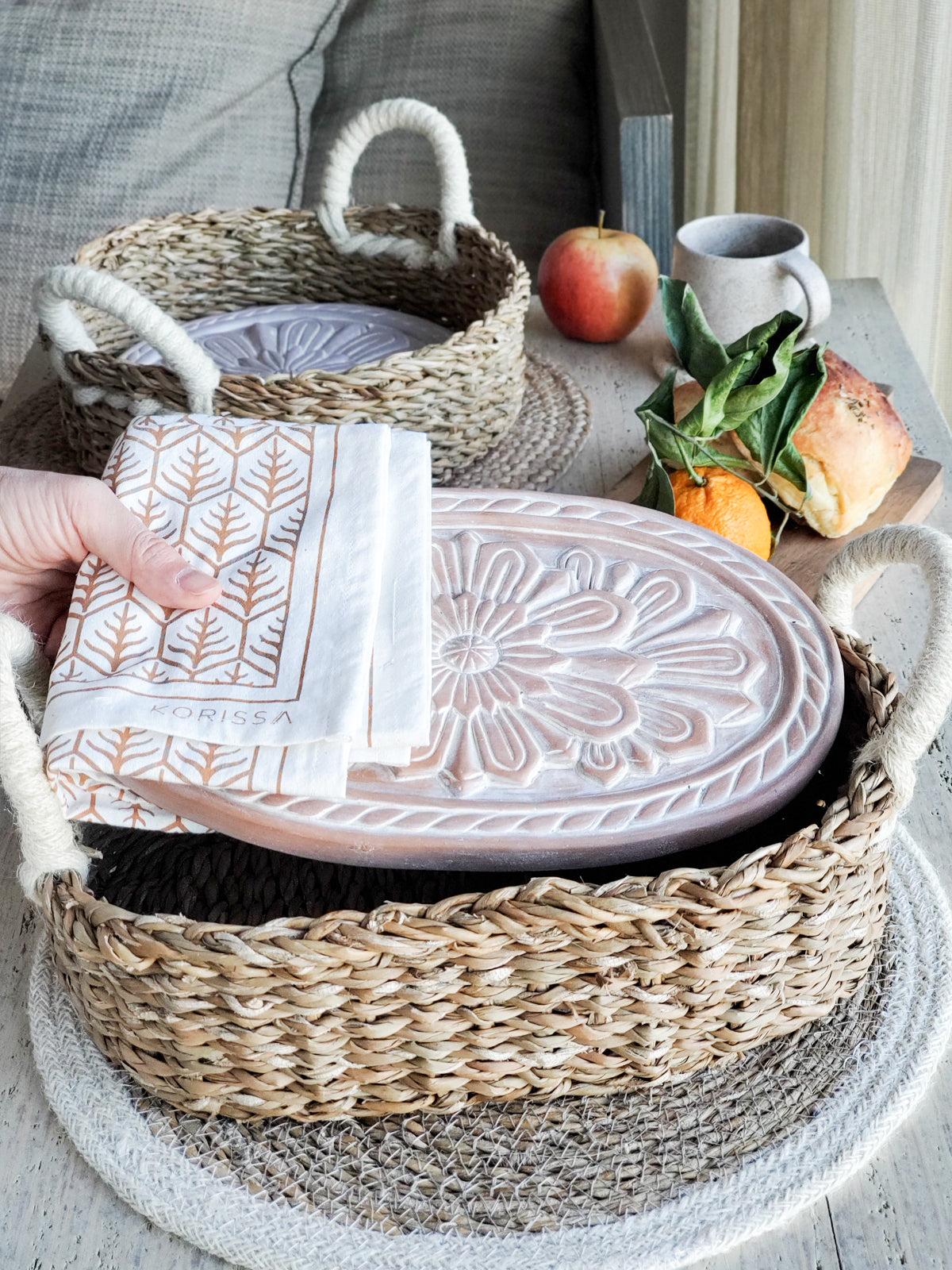 Terracotta bread warmer with engraved flower, woven seagrass serving basket, and natural cotton tea towel. — view 3