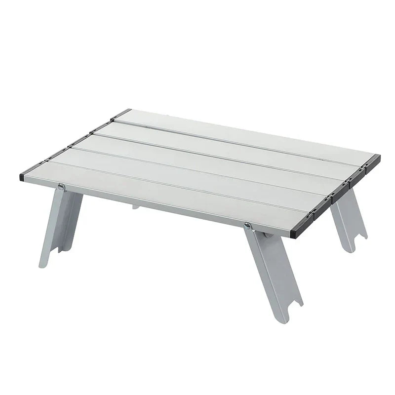 Foldable mini camping table in silver aluminum alloy set up outdoors for a picnic or barbecue