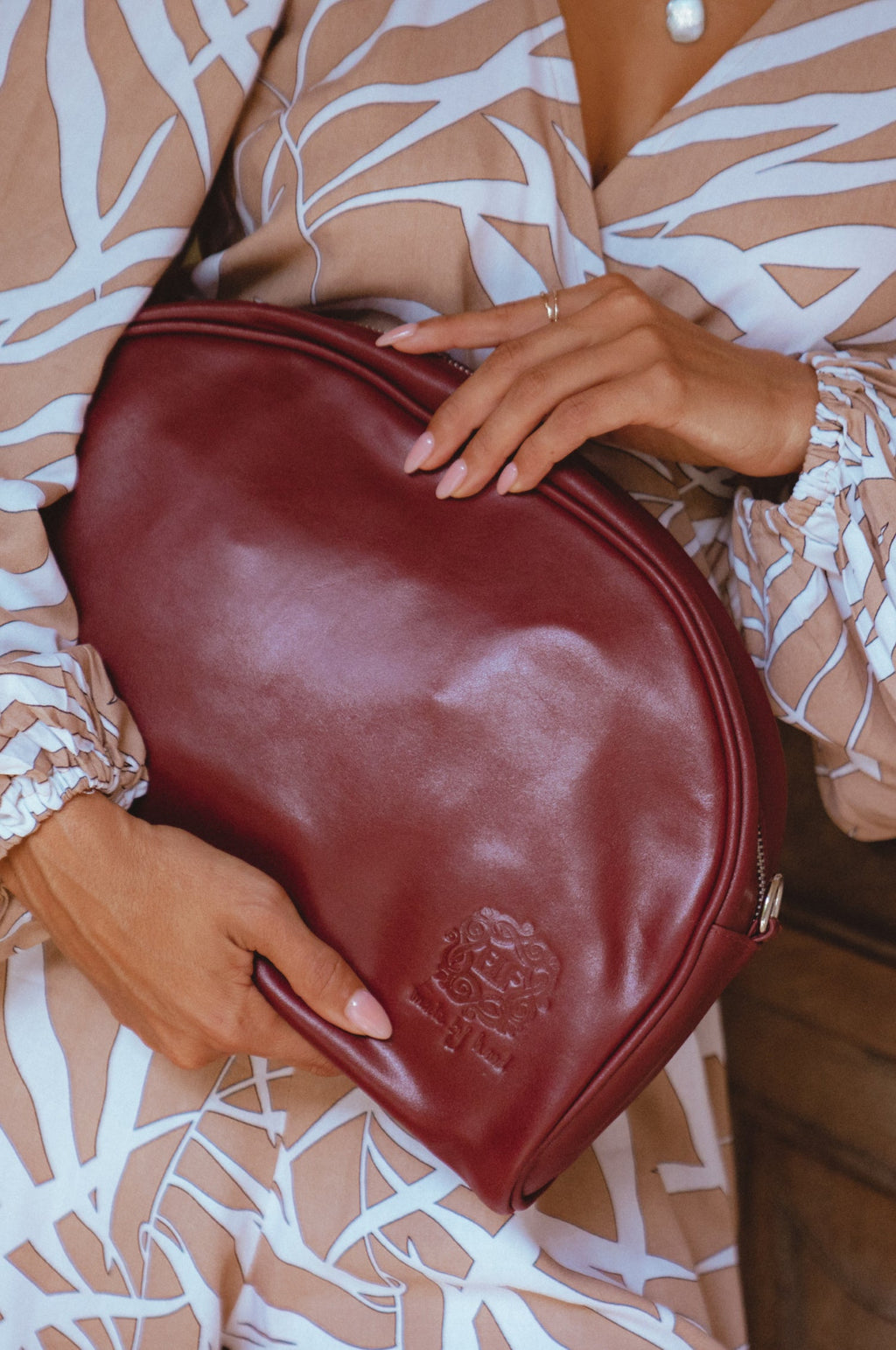 Red genuine leather Sabine handbag with adjustable strap, styled as a crossbody bag or oversized clutch.