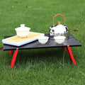 Portable foldable camping table with carry bag set up for an outdoor picnic or barbecue