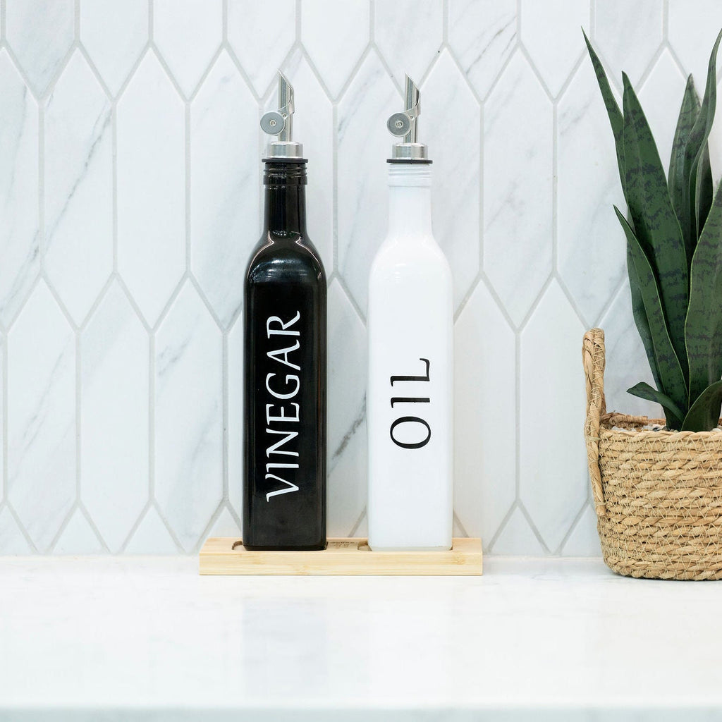 Black and white opaque glass oil and vinegar dispenser bottles on a smooth bamboo tray — view 4