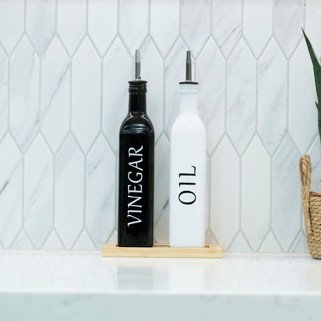 Black and white opaque glass oil and vinegar dispenser bottles on a smooth bamboo tray