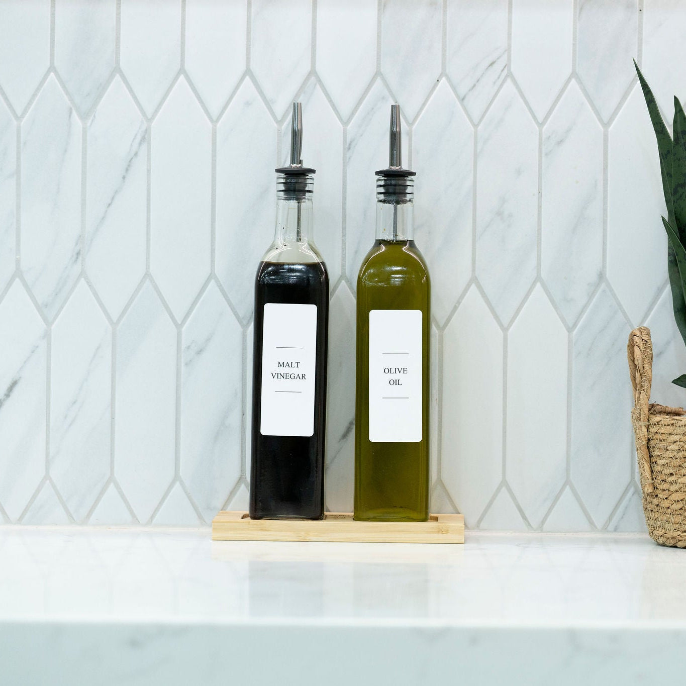Two 500ml clear glass oil and vinegar bottles with metal pourers on a natural bamboo tray — view 2