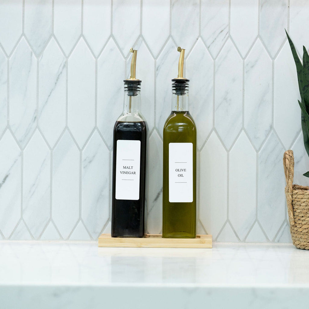 Two 500ml clear glass oil and vinegar bottles with metal pourers on a natural bamboo tray — view 3