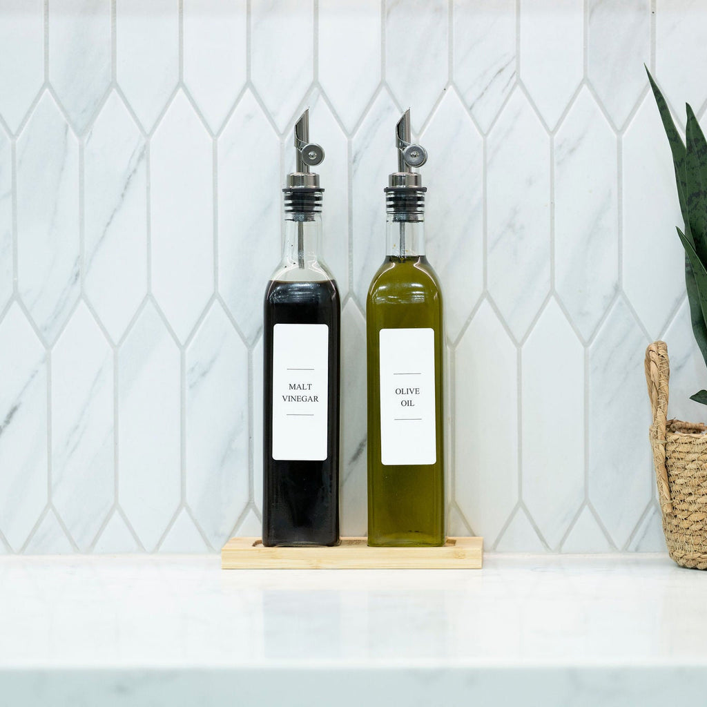 Two 500ml clear glass oil and vinegar bottles with metal pourers on a natural bamboo tray — view 5
