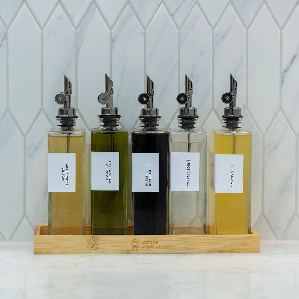 5-piece clear glass oil and vinegar bottle set with precision pourers on a natural bamboo tray