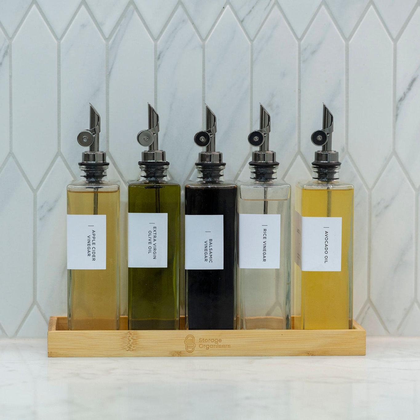 5-piece clear glass oil and vinegar bottle set with precision pourers on a natural bamboo tray