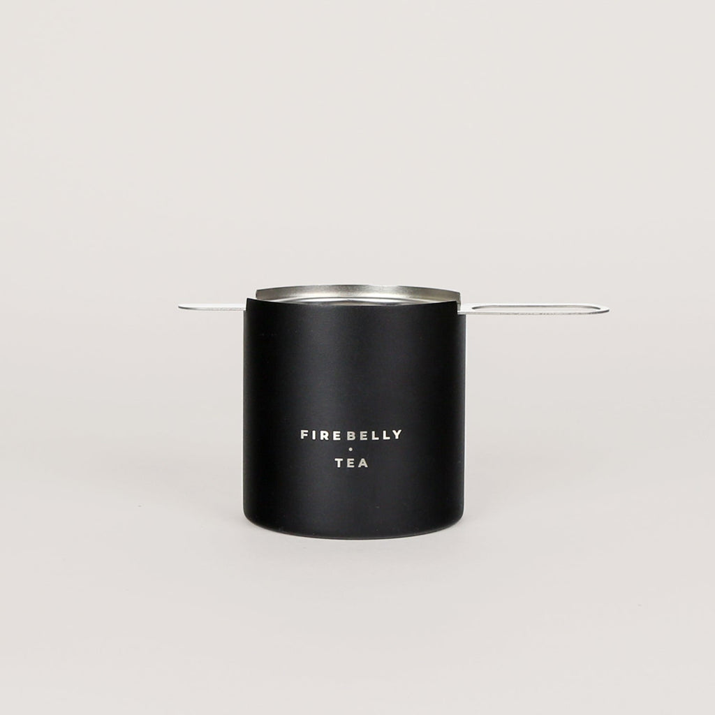 Black loose leaf tea strainer and fine mesh infuser resting on a matching catch cup. — view 5