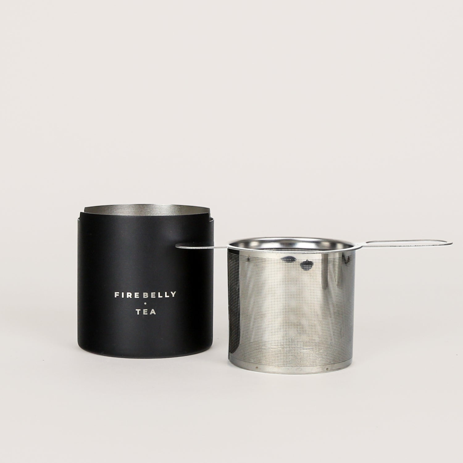 Black loose leaf tea strainer and fine mesh infuser resting on a matching catch cup.