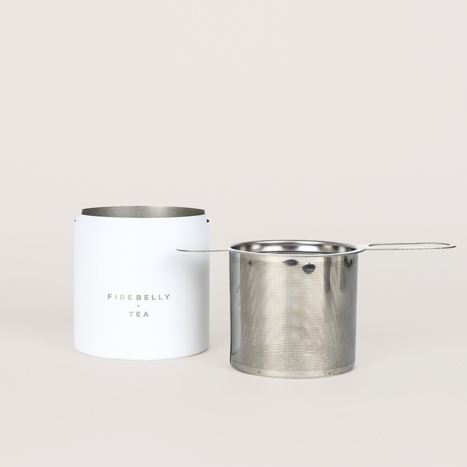 Black loose leaf tea strainer and fine mesh infuser resting on a matching catch cup. — view 2