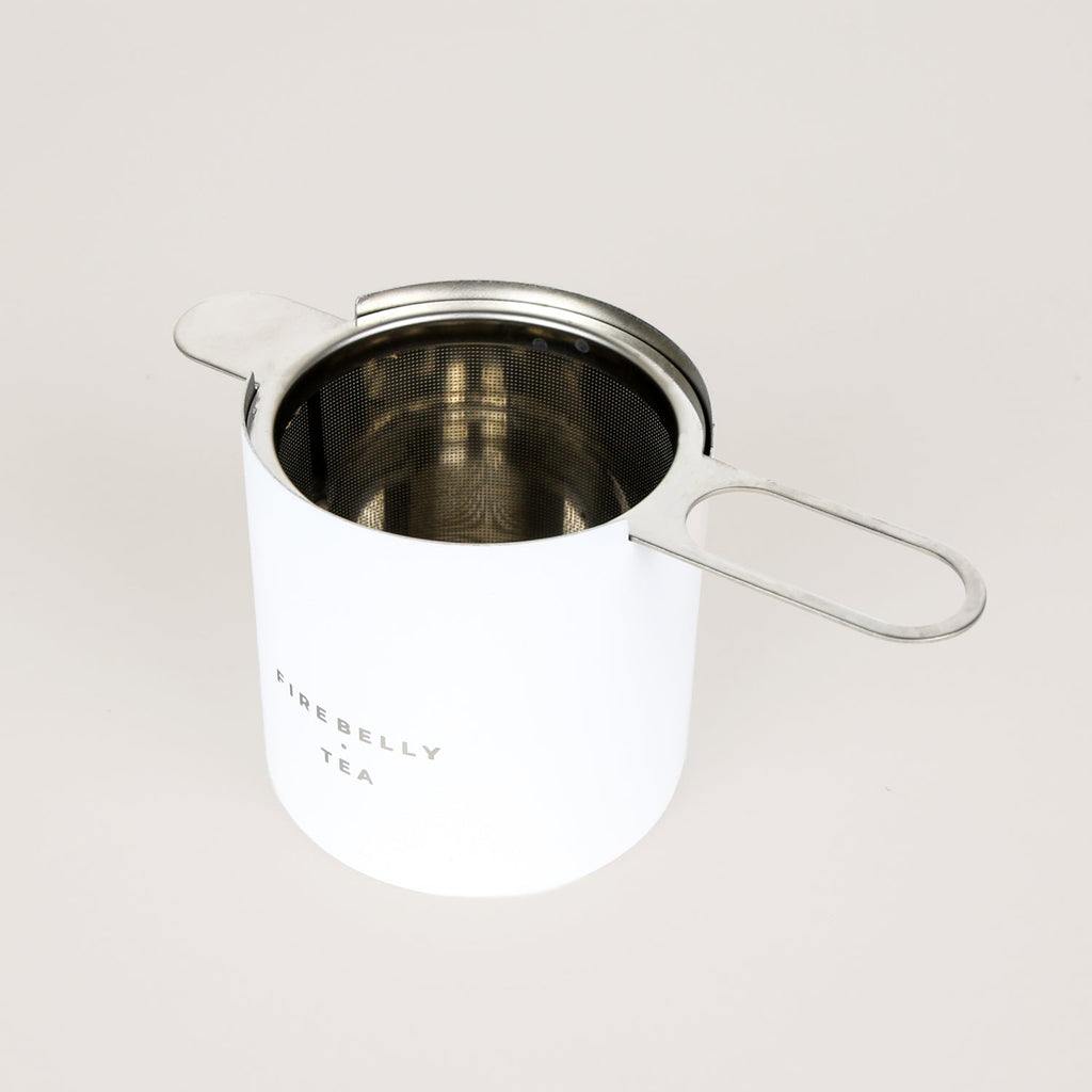 Black loose leaf tea strainer and fine mesh infuser resting on a matching catch cup. — view 3