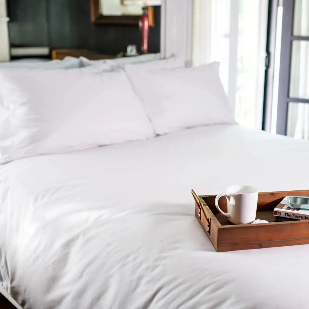 Folded stack of crisp T-300 white combed cotton bed sheets with matching pillowcases — view 4