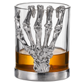 Skeleton whiskey glass tumbler with detailed bone hand stem, clear glass cup holding amber liquor