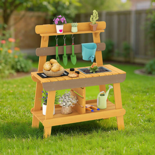Yellow wooden outdoor mud kitchen for kids with play sink, grill, and gardening tools.