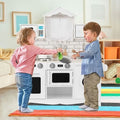 Wooden kids play kitchen set with washing machine, sink, oven, and cooking accessories.
