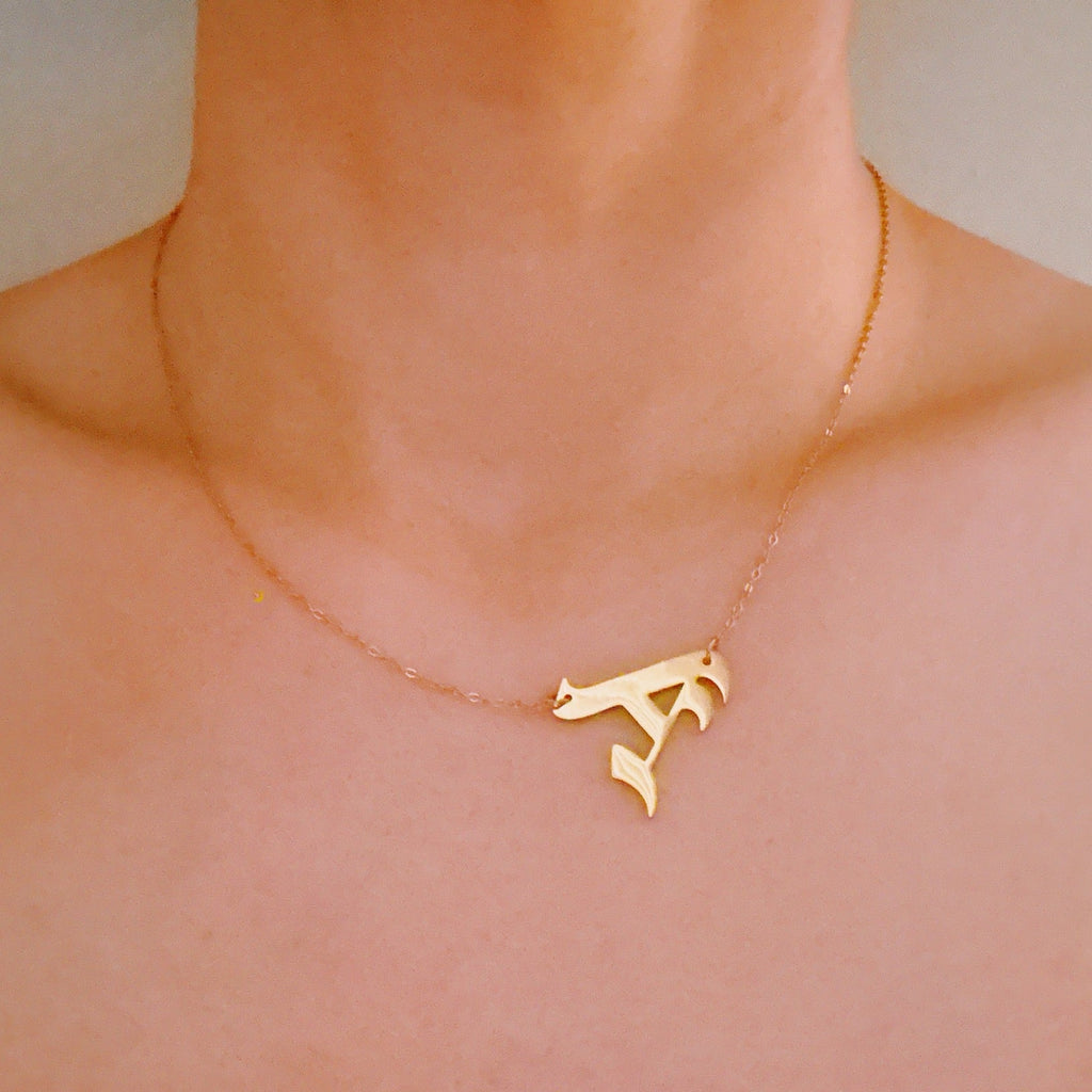 18K gold plated stainless steel gothic initial necklace hanging elegantly to the side — view 5