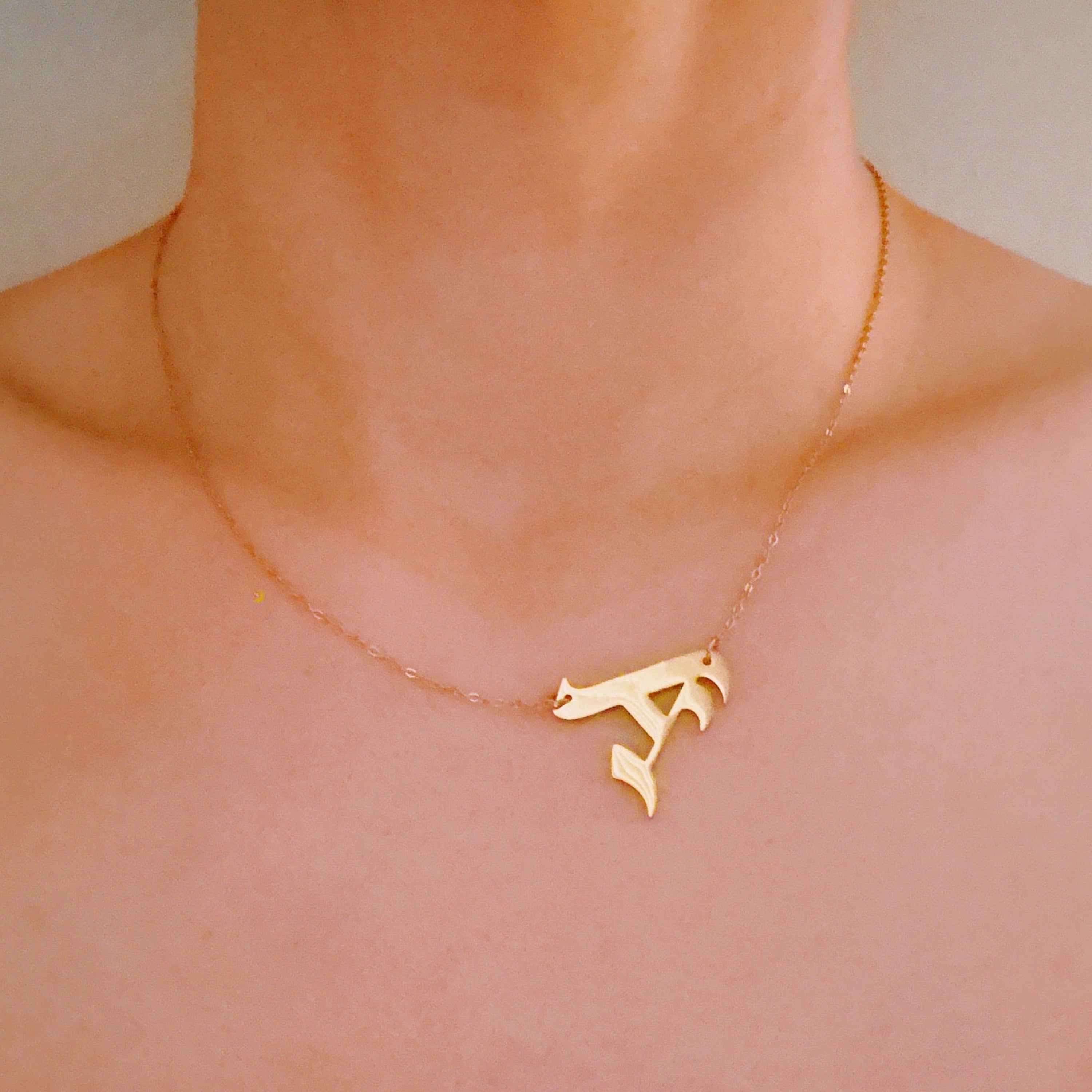 18K gold plated stainless steel gothic initial necklace hanging elegantly to the side — view 5