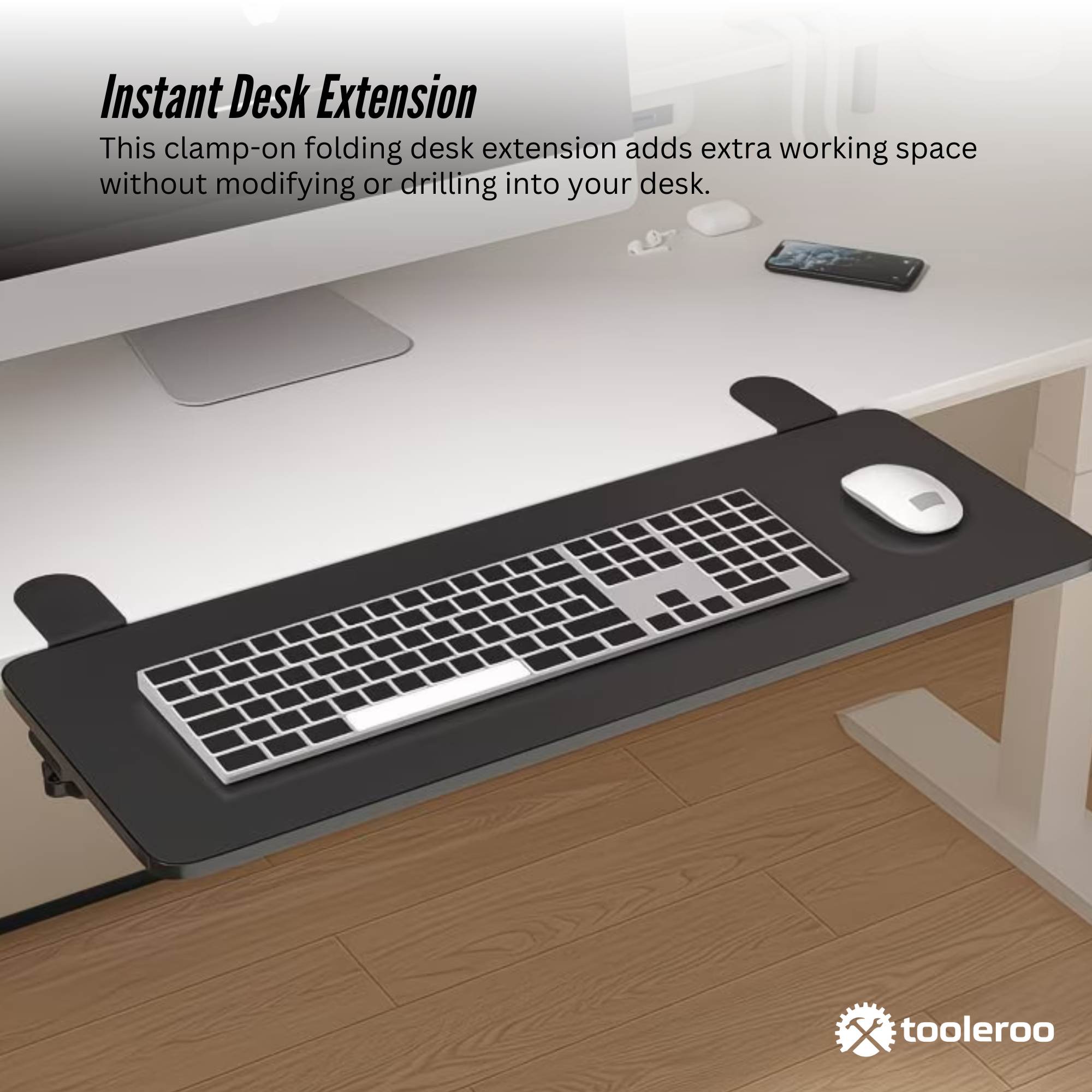 Black folding clamp-on desk extension tray with steel mounts attached to a wooden desk — view 3