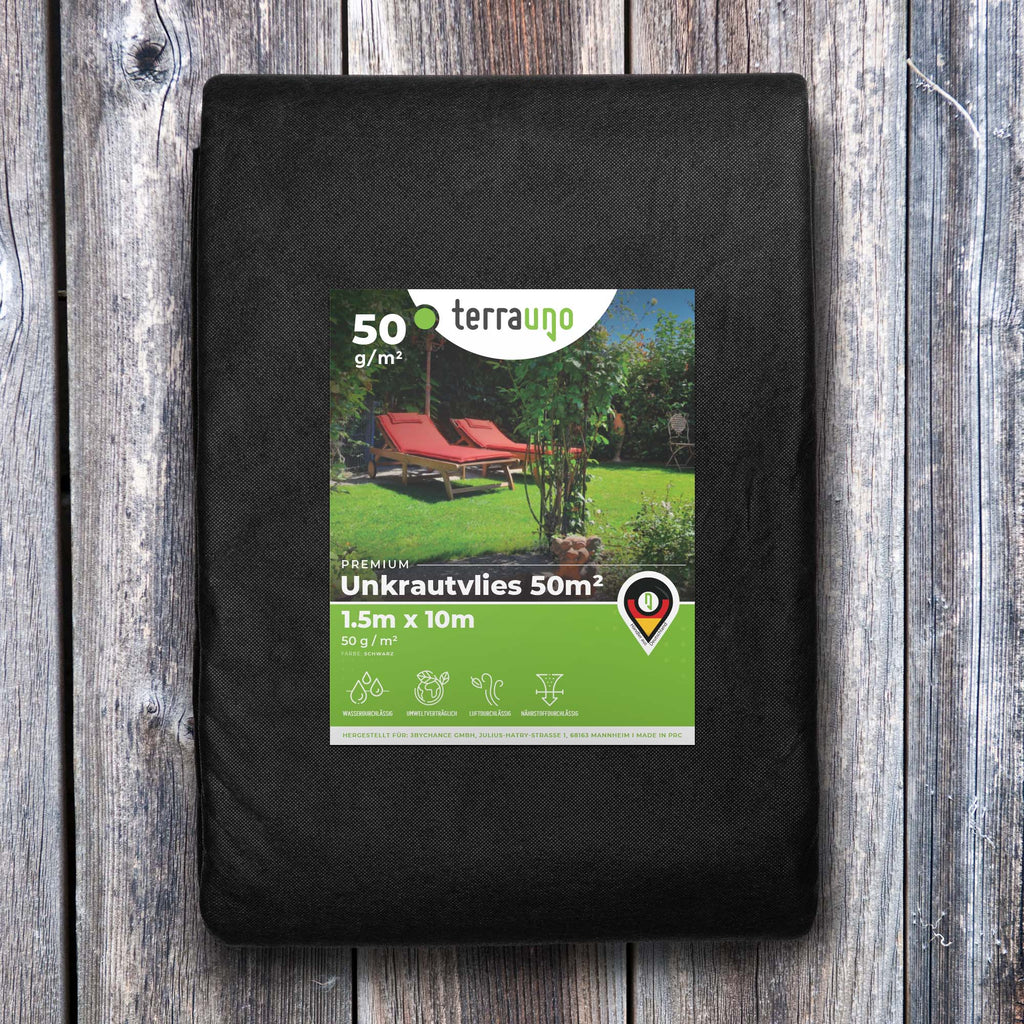 Water-permeable weed barrier fleece unrolled on a garden bed for landscaping and weed prevention. — view 5