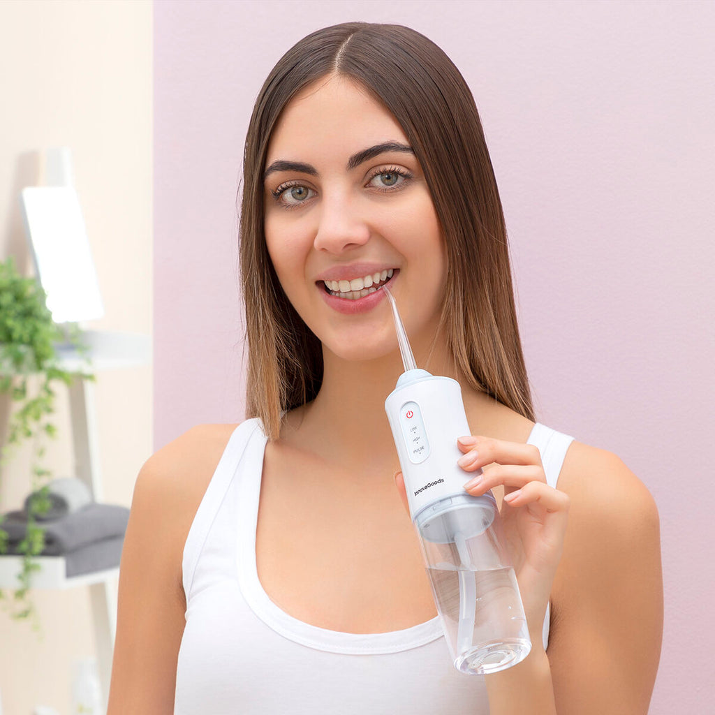 Portable blue and white cordless water flosser with interchangeable cleaning heads and USB cable.
