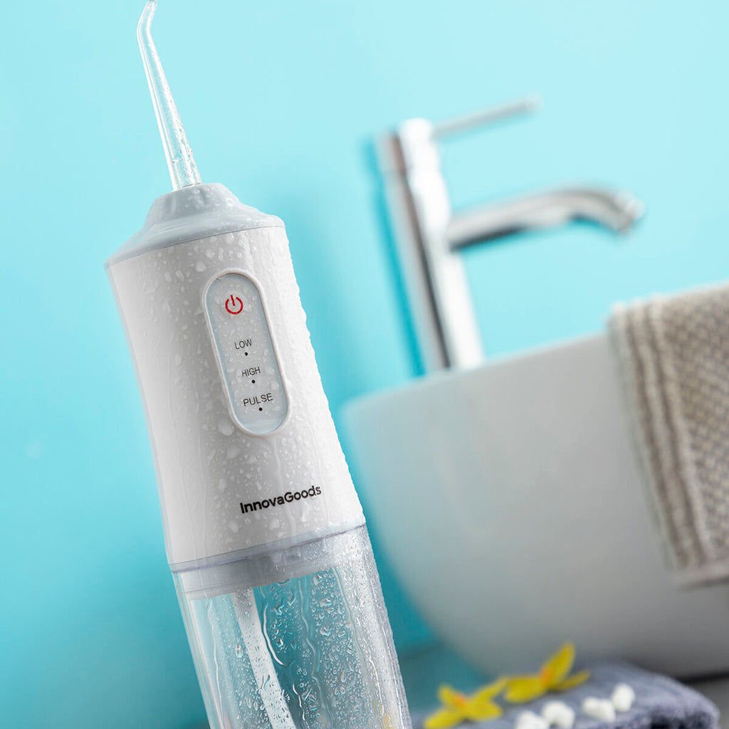 Portable blue and white cordless water flosser with interchangeable cleaning heads and USB cable. — view 8