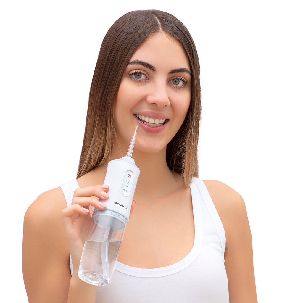 Portable blue and white cordless water flosser with interchangeable cleaning heads and USB cable. — view 5