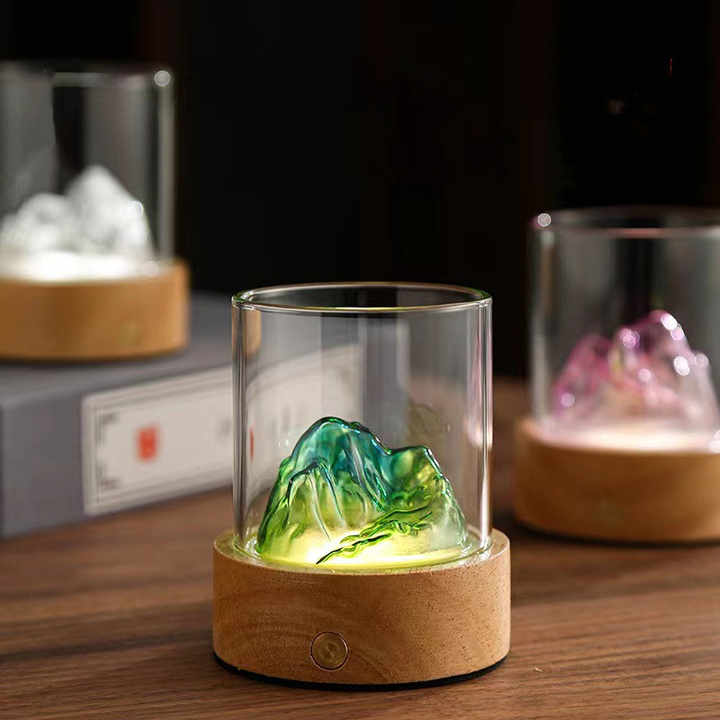 Blue-green glass mountain ambient night light with a solid wood base and glowing warm illumination — view 2