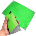 Green and grey waterproof portable camping mat folded out for outdoor picnic and beach use