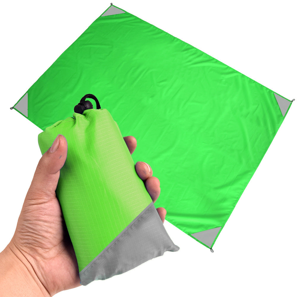 Green and grey waterproof portable camping mat folded out for outdoor picnic and beach use