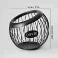 Black handcrafted vintage iron coffee capsule storage basket holding pods on a kitchen countertop