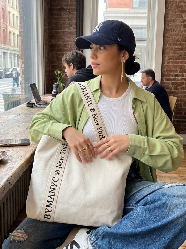 Cream canvas tote bag with black logo typography on reinforced shoulder straps