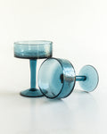 Handblown hammered coupe cocktail glasses pair in colored recycled glass on a table