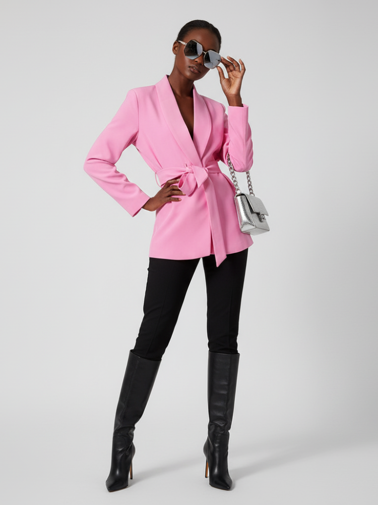 Vibrant pink women's blazer with matching tie belt and smooth tuxedo lapel on model.