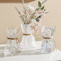 Wrinkled glass vase with natural twine accent and folded paper texture on a modern table