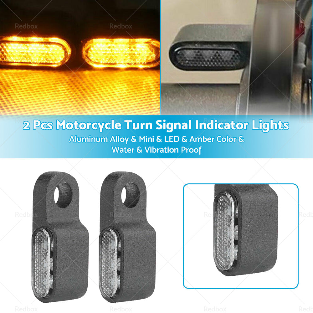 Two black aluminum mini LED motorcycle turn signals emitting bright amber blinker light.