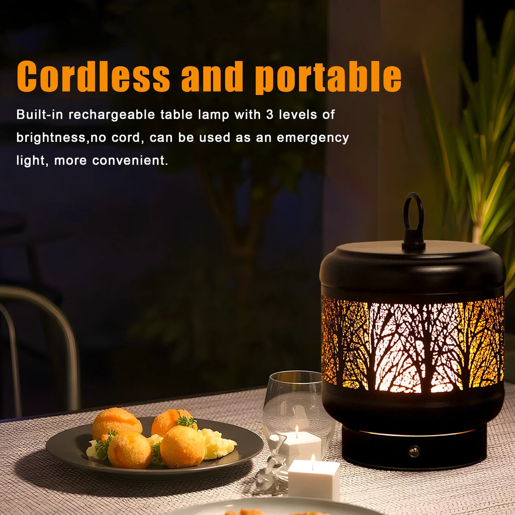 Rechargeable metal desk lamp with tree silhouette cutouts glowing in warm light on a table
