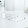 Clear acrylic drawer organizer set holding makeup and desk supplies on a vanity
