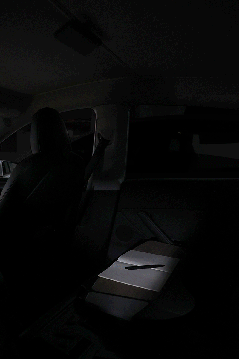 Portable LED light with MagSafe wireless charging illuminating an electric vehicle interior — view 2