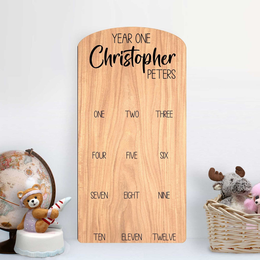 Custom wooden baby milestone photo board displaying twelve months of pictures with personalized cut out name — view 3