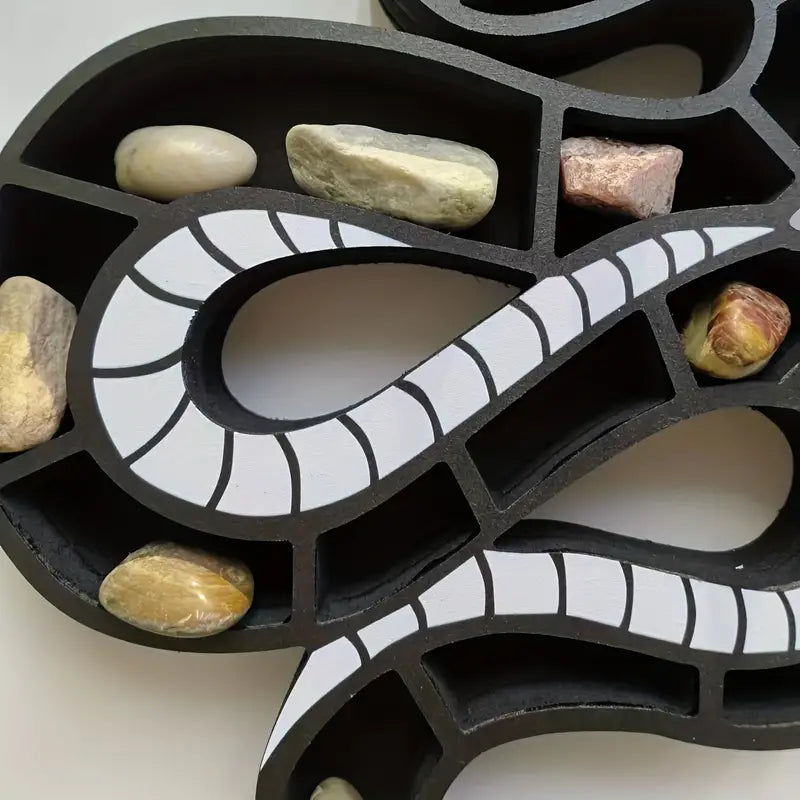 Black wooden snake shaped wall shelf displaying crystals and small plants on a wall — view 5