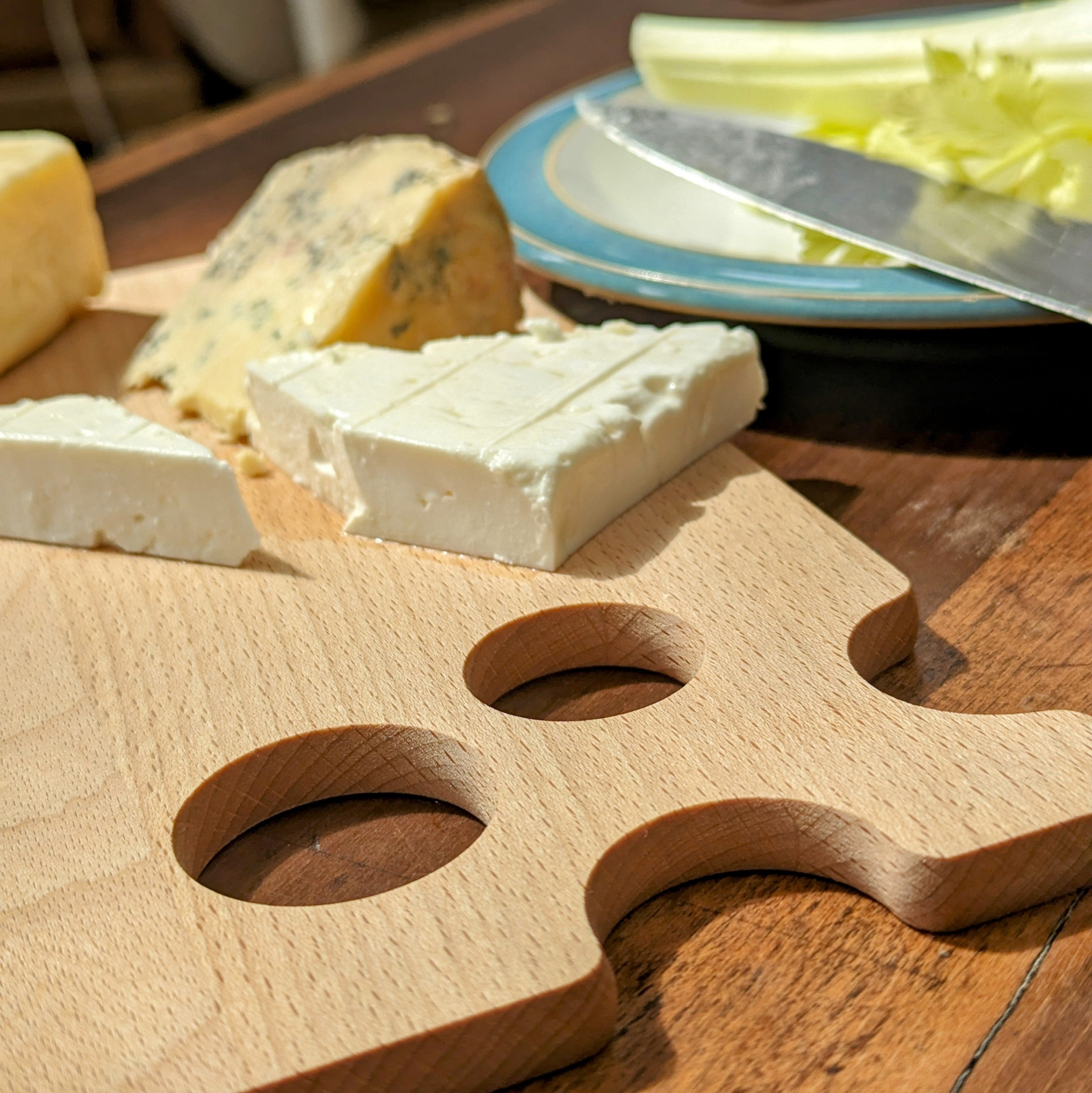 Beech wood cheese board with quirky cutout holes design, resting flat on a table surface — view 5