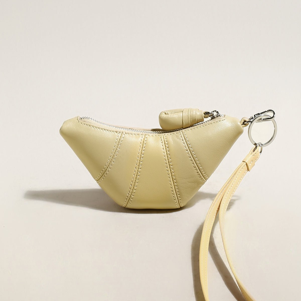Soft vegan leather croissant mini pouch bag charm with wrist strap and zipper closure. — view 5