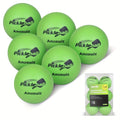 Six green foam training pickleballs arranged in a white mesh storage bag for indoor practice