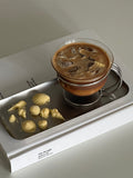 Clear vintage glass coffee cup resting in a sleek minimalist stainless steel wire holder