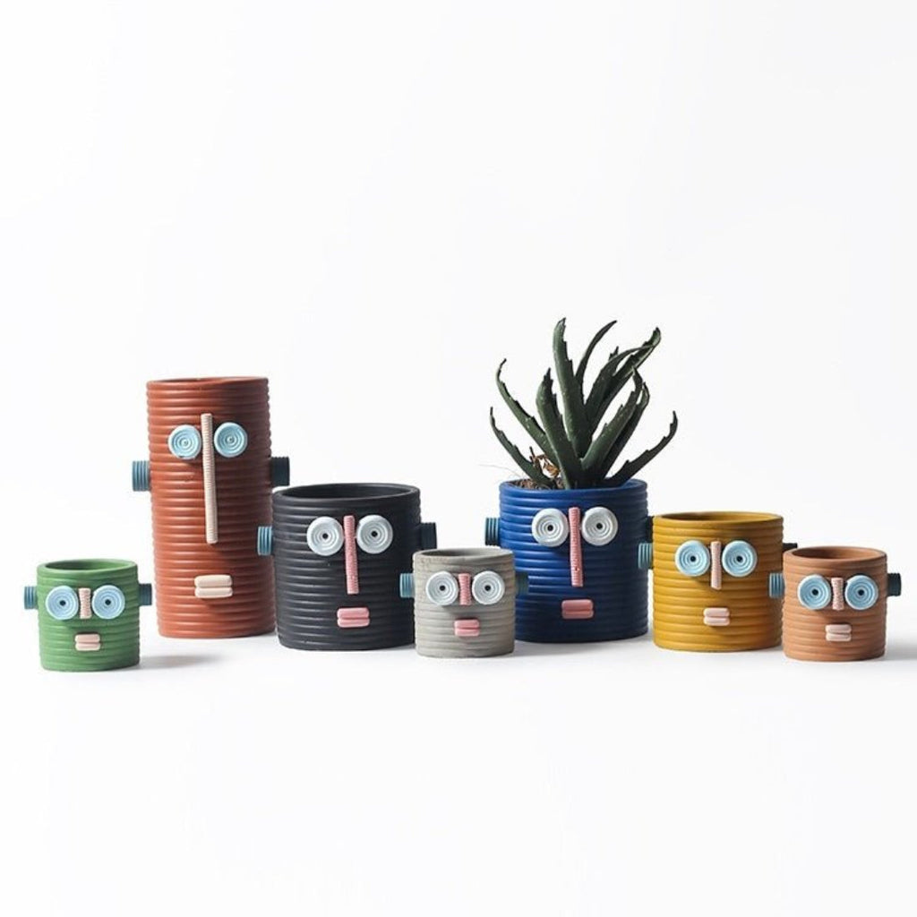 Handmade ceramic dummy robot flower pot displaying a green succulent plant on a garden patio. — view 2