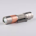 Compact titanium everyday carry flashlight with a metallic finish and tactical tail switch button