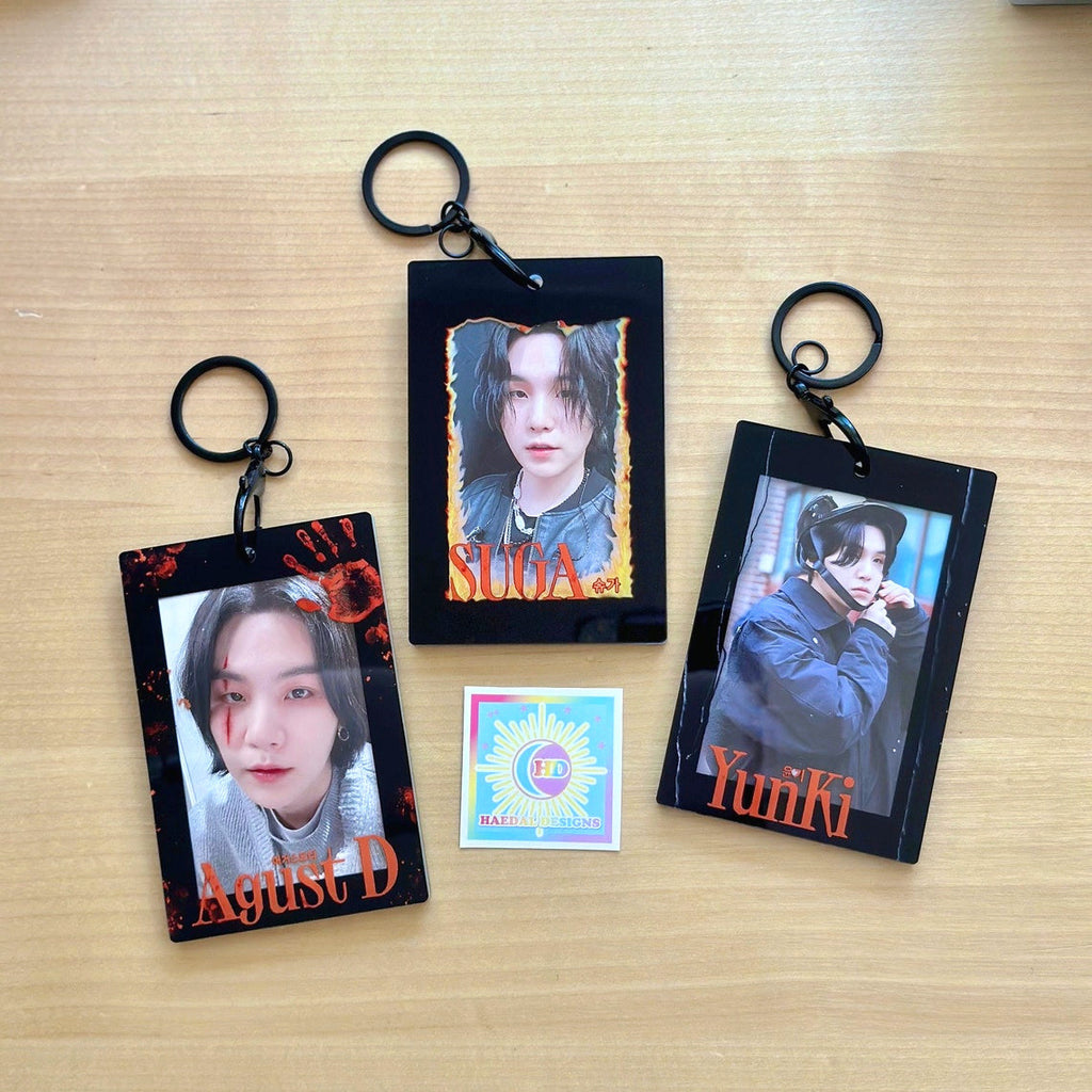 Clear acrylic photocard holder keychain displaying a card, with black chain and claw clasp.