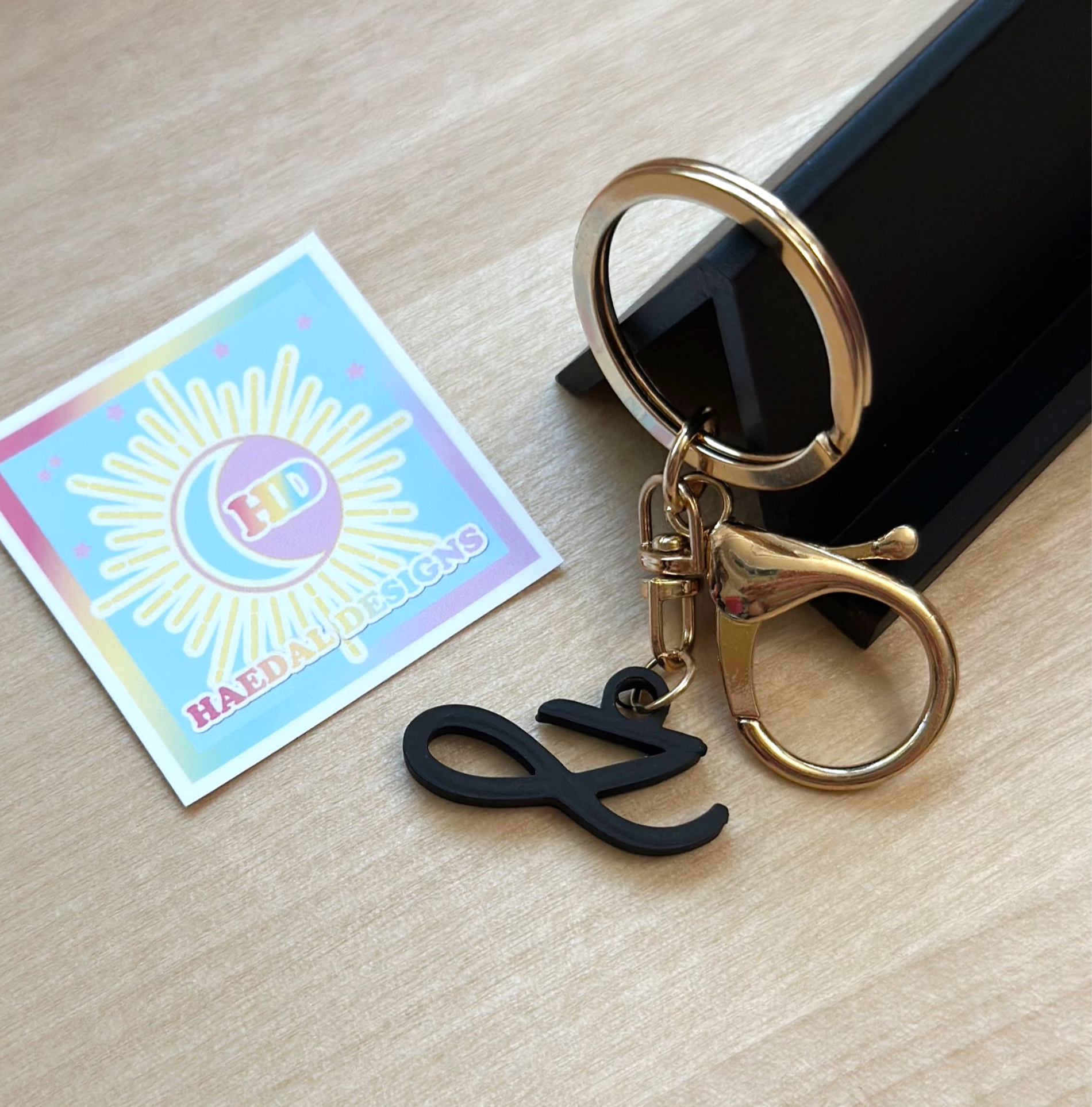 Custom Jung Kook logo charm keychain in vibrant PLA attached to a gold metal keyring