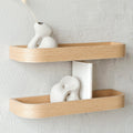 Natural oak wood floating wall shelf holding small decorative plants and picture frames in modern home